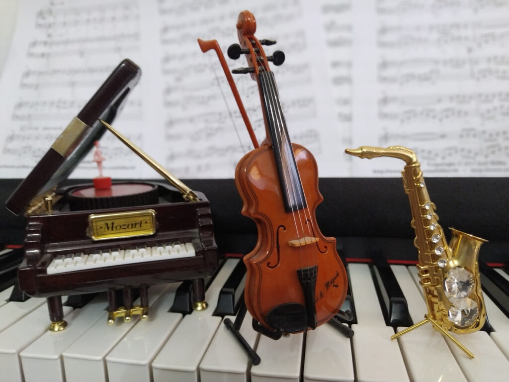 piano keyboard with miniature piano, saxo and cello